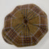 A top-down view of a small, round, multi-panel cap made from brown tweed fabric with a blue and purple plaid pattern, set against a plain white background.