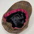 A brown and purple plaid flat cap viewed from the inside, showing a black satin lining and a vibrant pink inner trim.