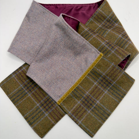 A folded tweedscarf shown on a plain white background, in a muted lavender-gray herringbone and an olive-brown plaid.