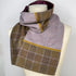 A folded plaid scarf in brown, purple, and gold tones, displayed on a cream mannequin torso against a plain white background.